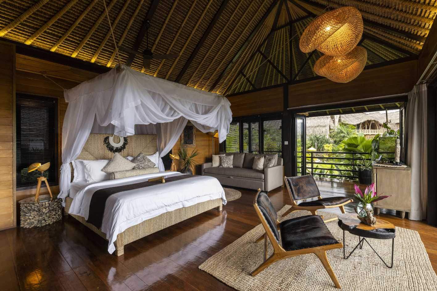 A bedroom at Samanvaya Luxury Resort with a white bed and two brown chairs.