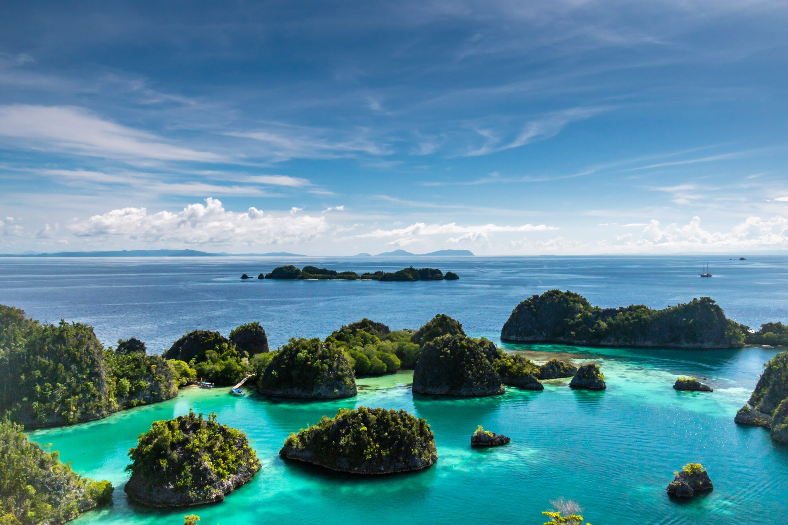A view of islands with trees and blue water at Raja Ampat landmark in Indonesia.