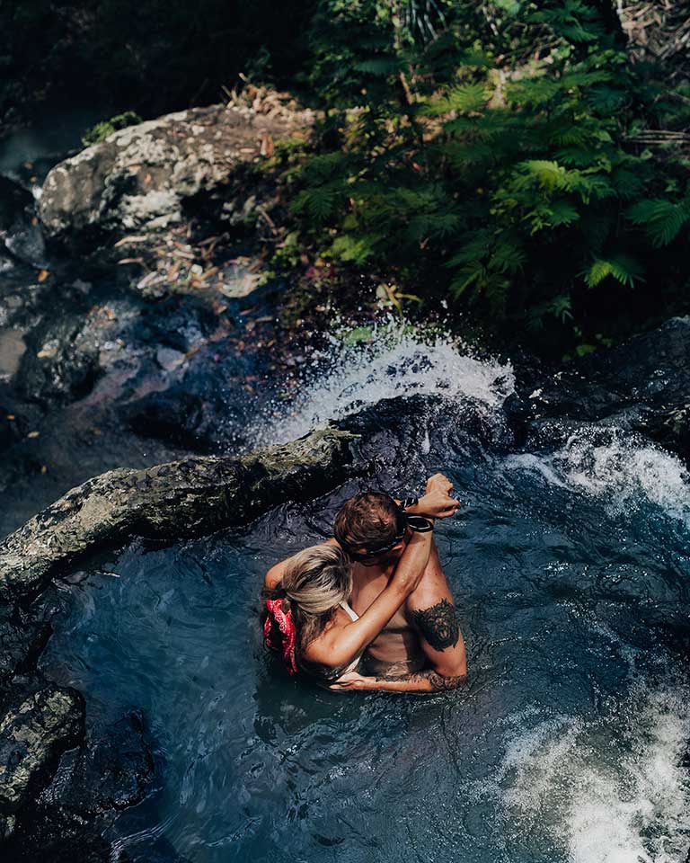 A couple swims in a waterfall with several pools in Sidemen, Bali.