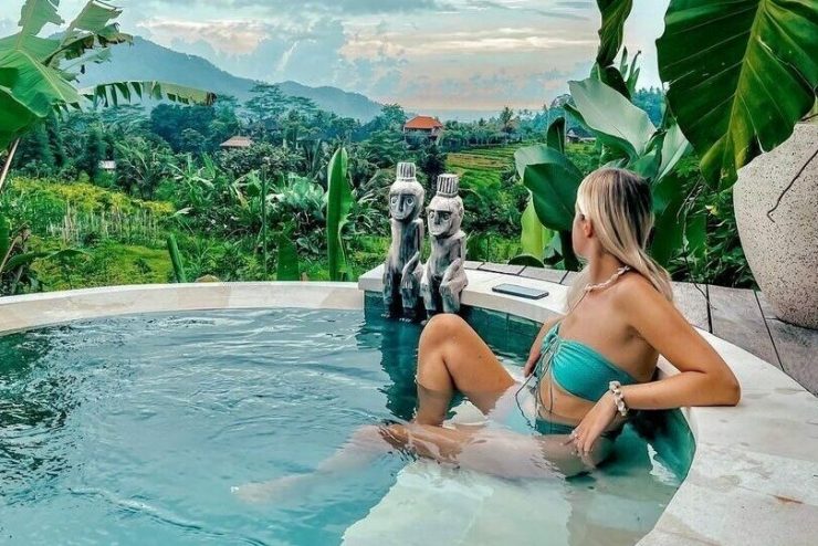 A woman soaks in a private pool while looking at green mountains.