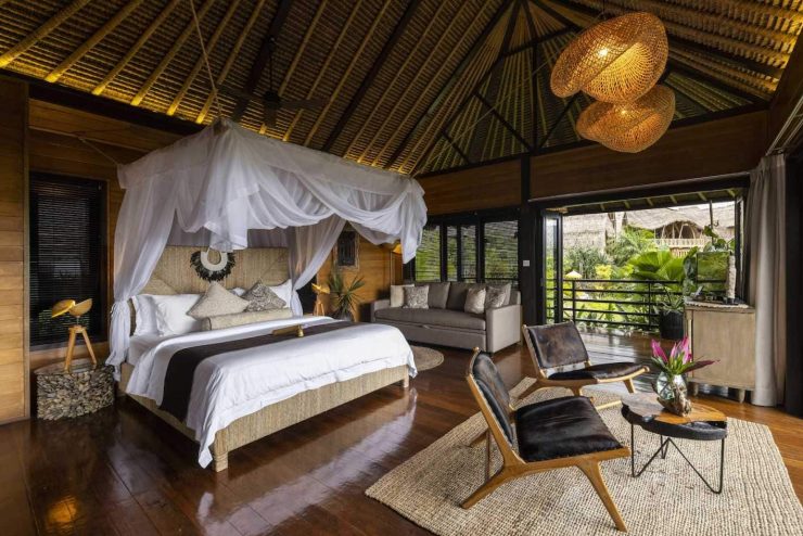 A bedroom at Samanvaya Luxury Resort with a white bed and two brown chairs.